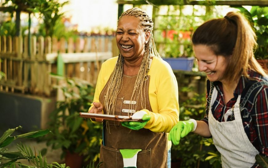 Multiracial women working inside glasshouse garden market - Green concept