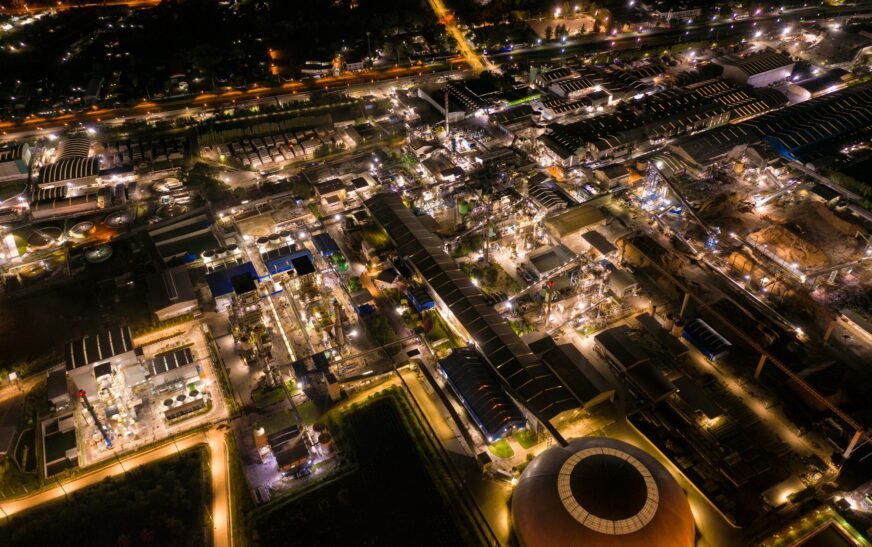 Industrial factory with chemical refinery and building material glowing light at night